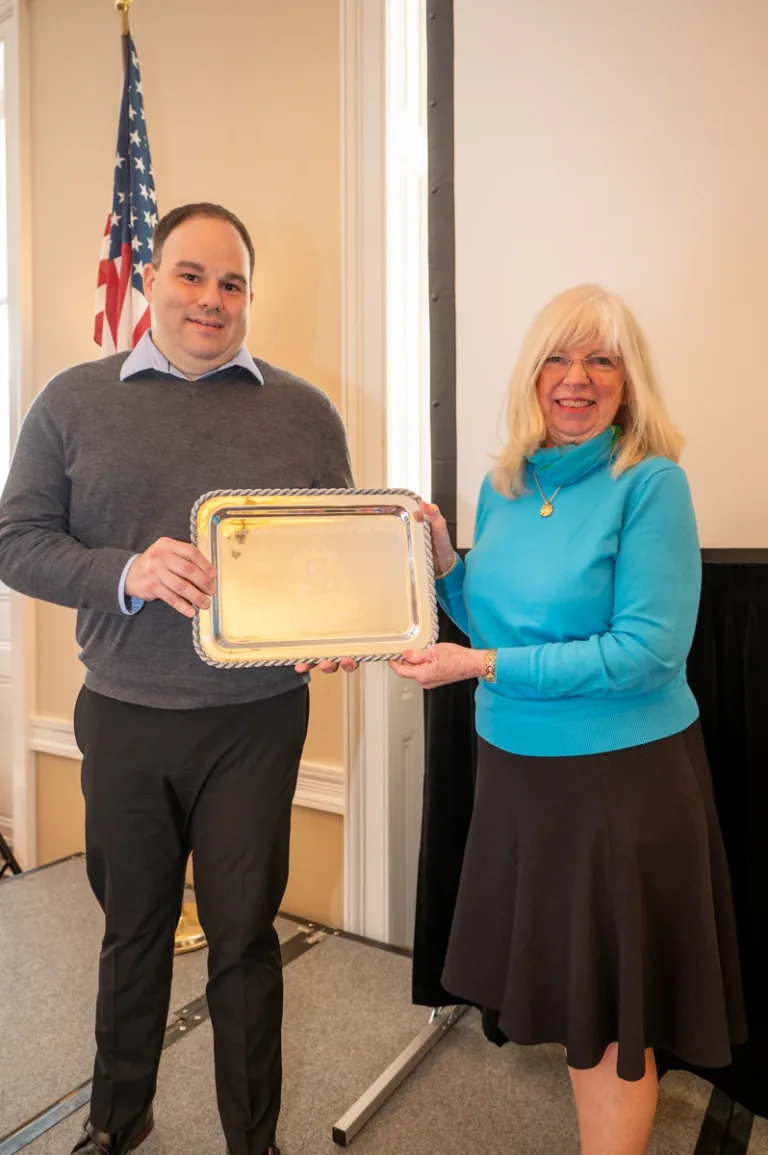 Man and woman holding a silver tray plaque at an award presentation