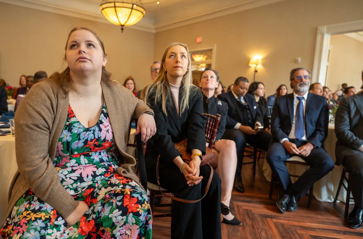 Audience members seated at banquet tables listening to a presentation