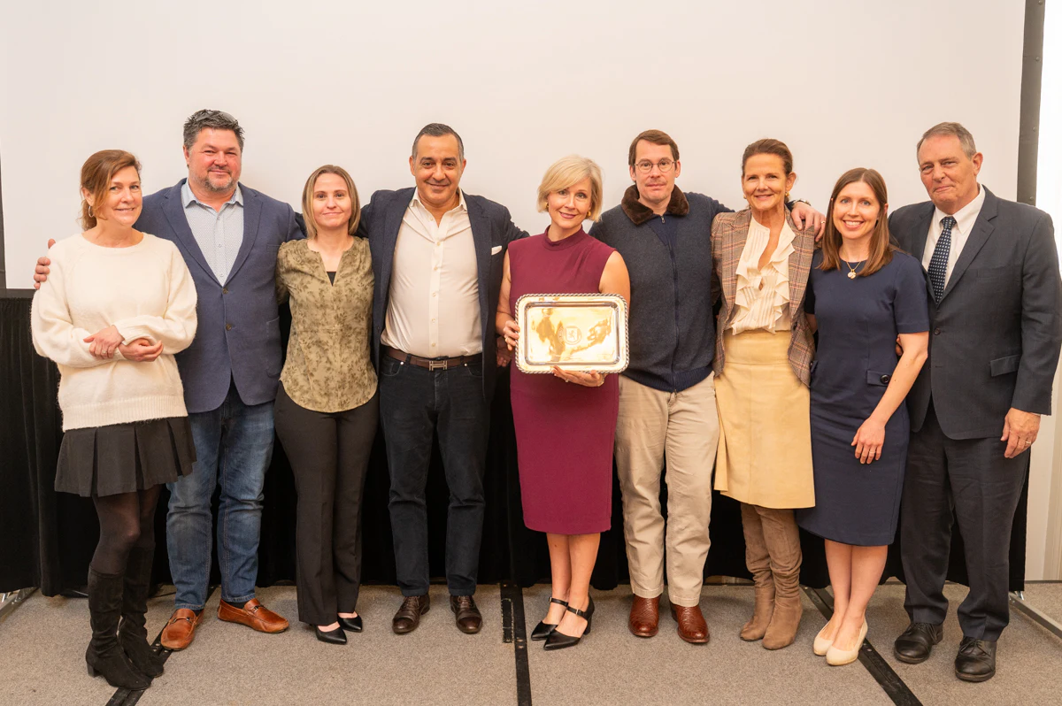 Group of ten people holding a framed award plaque at an event