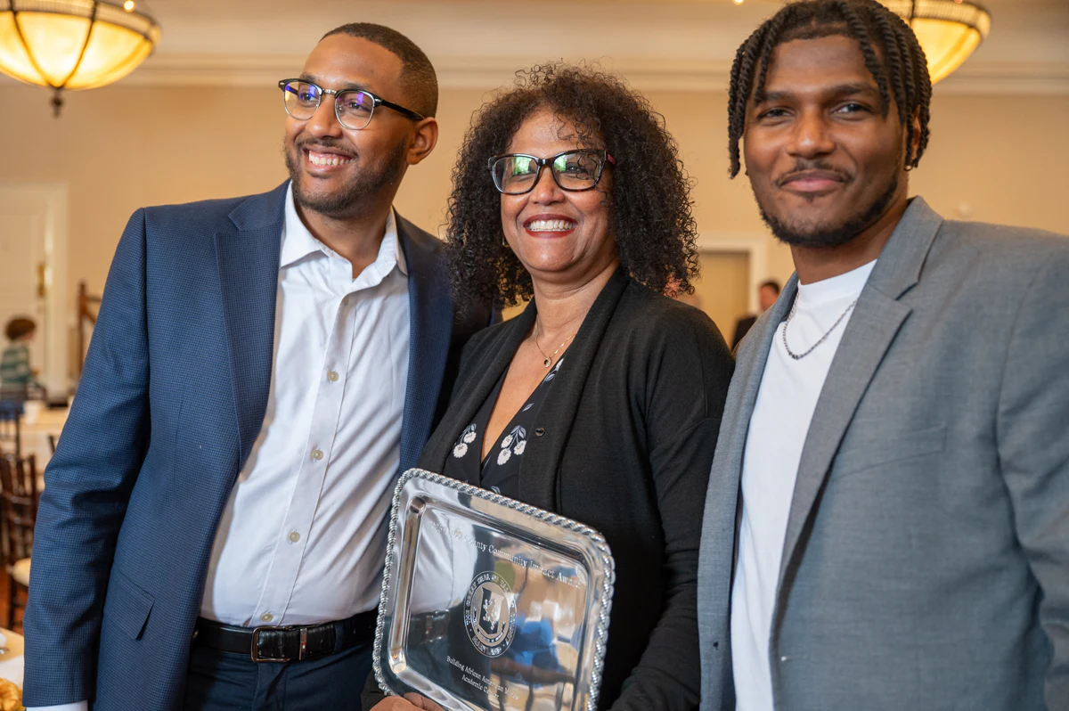 Three smiling people posing with a silver tray award