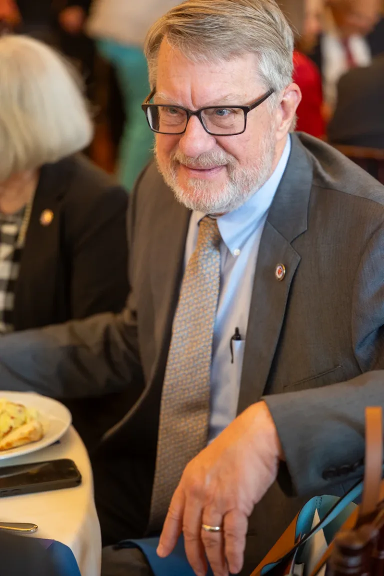 Man with glasses in gray suit seated at a banquet table