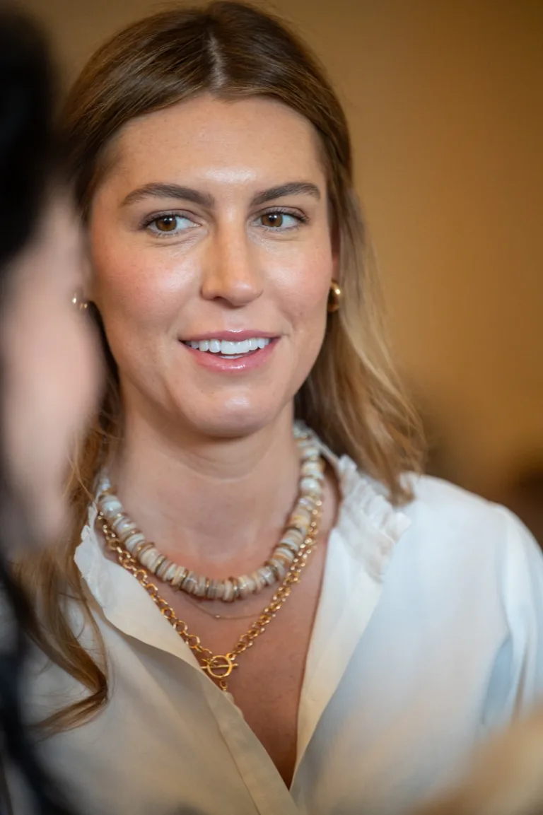 Smiling woman in pearl necklace at an indoor event