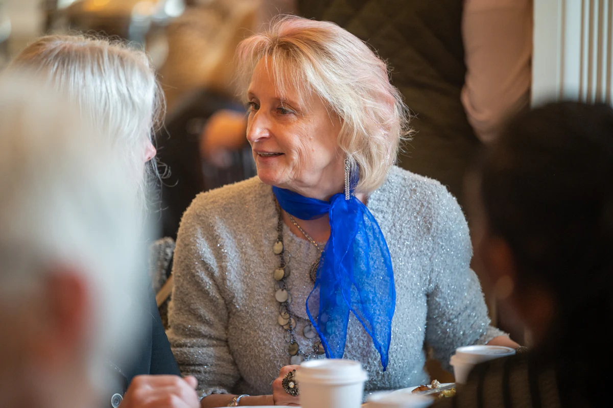 Woman with blonde hair and blue scarf seated at a banquet table
