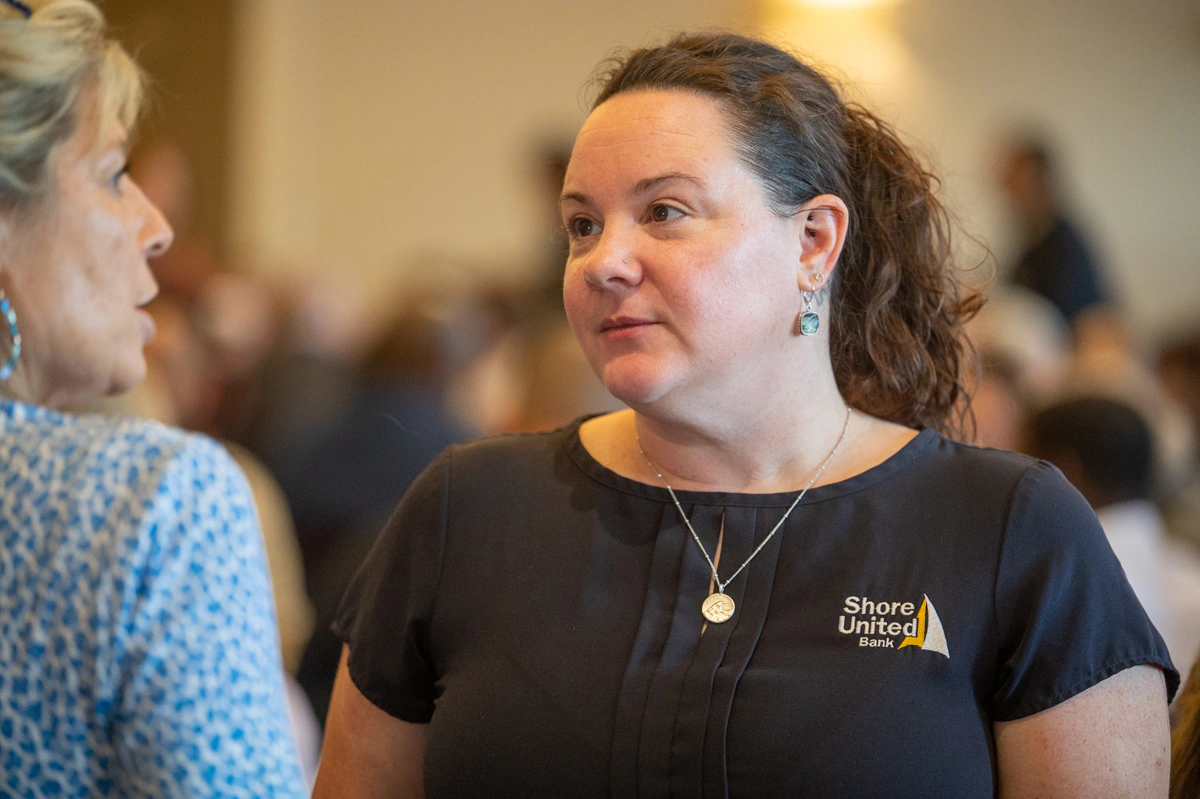 Woman in Shore United Bank shirt talking with a guest at an event
