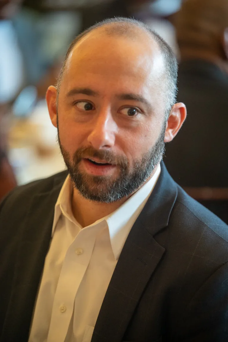 Bearded man in dark blazer speaking at a banquet table