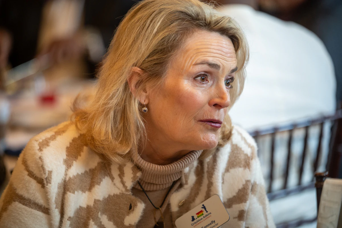 Woman with blonde hair in a patterned sweater and name badge speaks at an event
