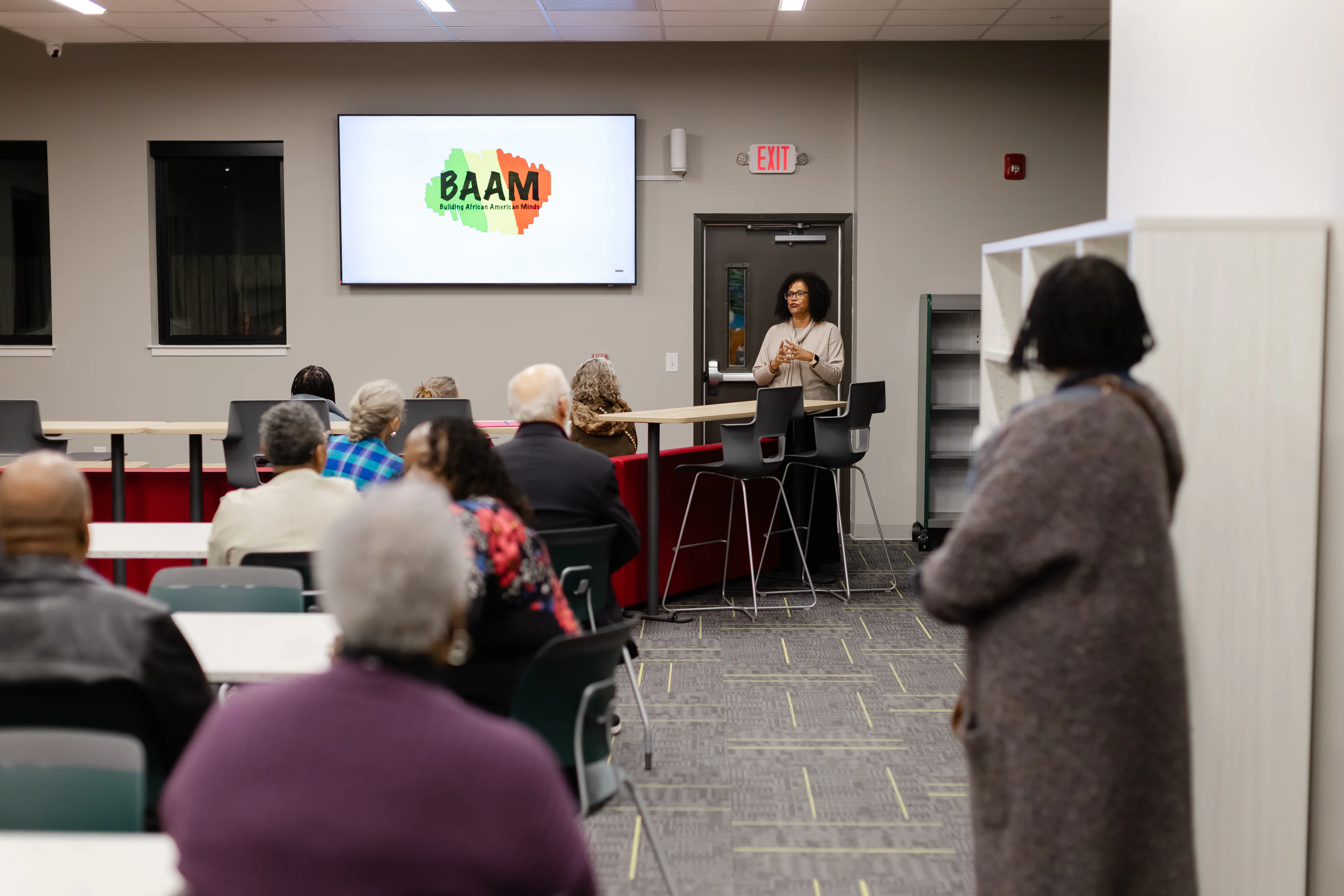 Woman presenting a BAAM Building African American Minds slide to seated attendees