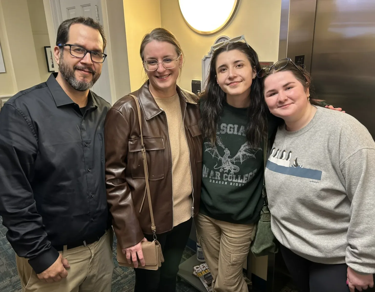 Four people posing together in a hallway