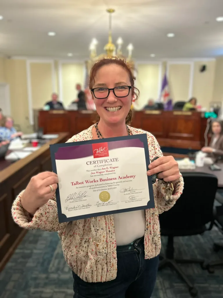 Woman holding a Talbot Works Business Academy certificate in a council chamber