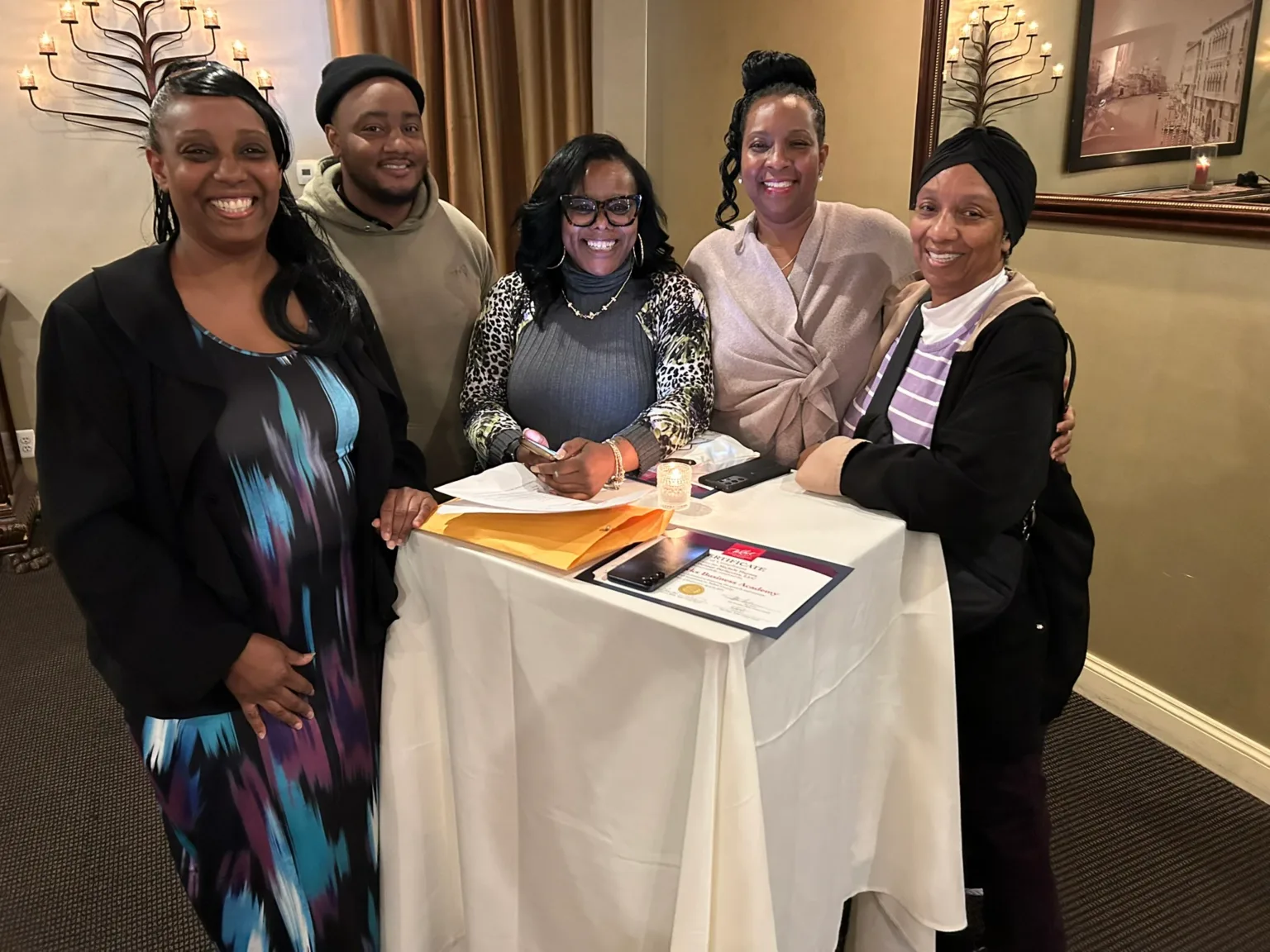 Group of five posing around a table with papers