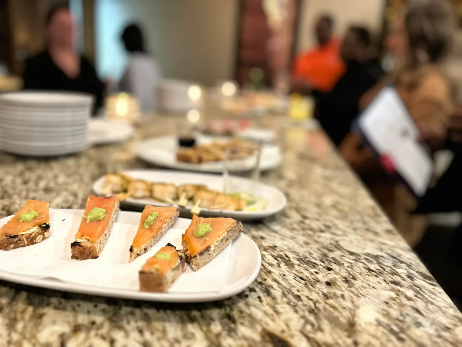 Appetizer crostini topped with salmon on a platter on a granite counter