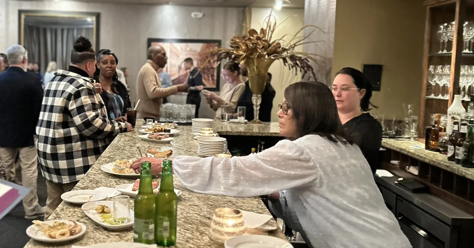Guests gathered at a granite counter with appetizers at an indoor reception