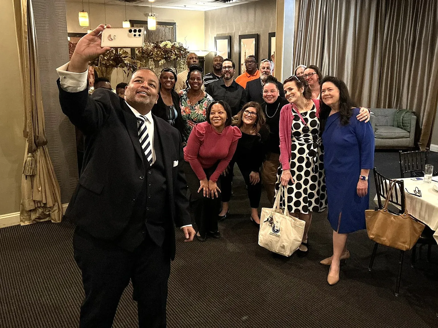 Man in suit taking a selfie with a group of guests at a reception