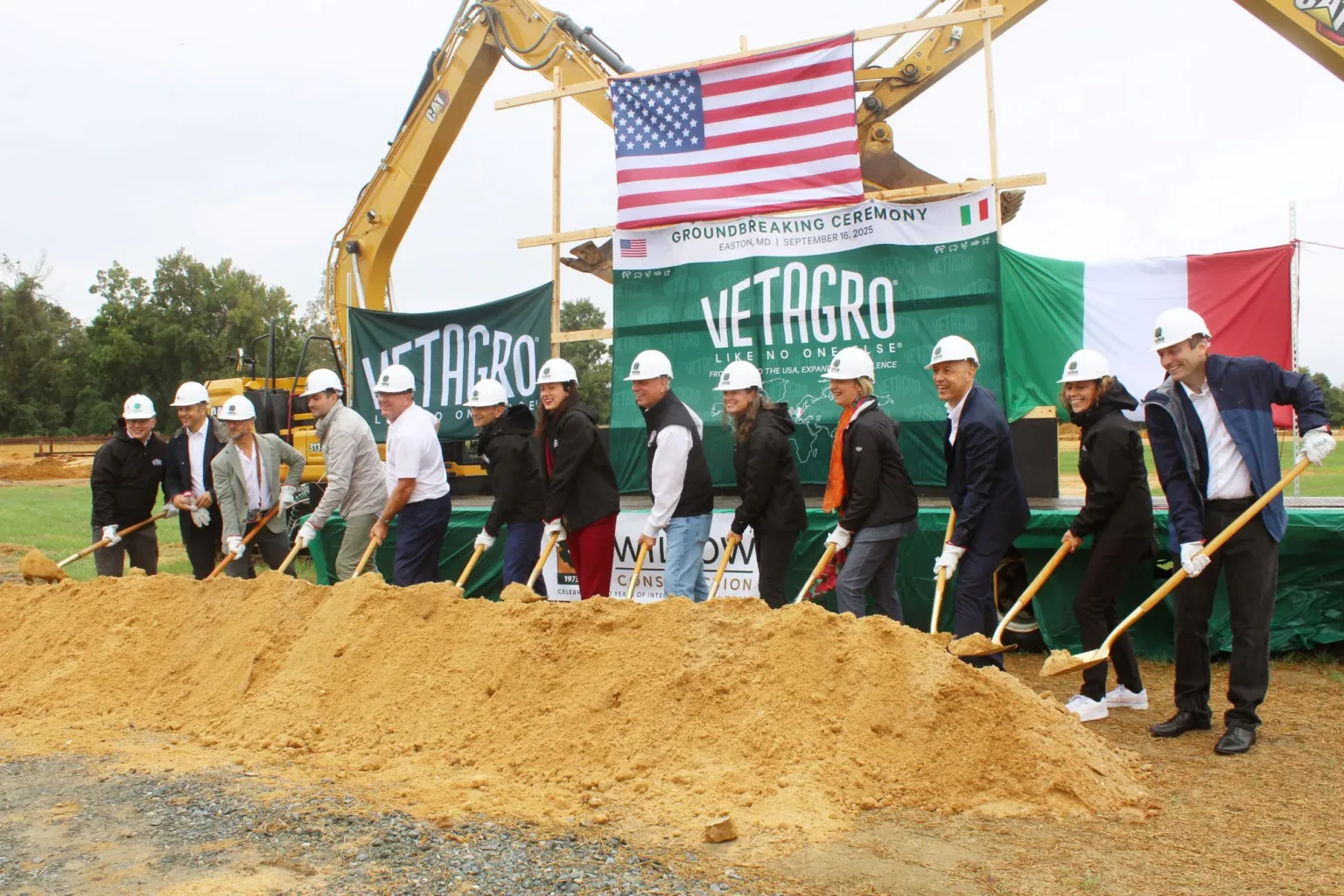 Officials in hard hats hold shovels at a groundbreaking beside a Vetagro banner.
