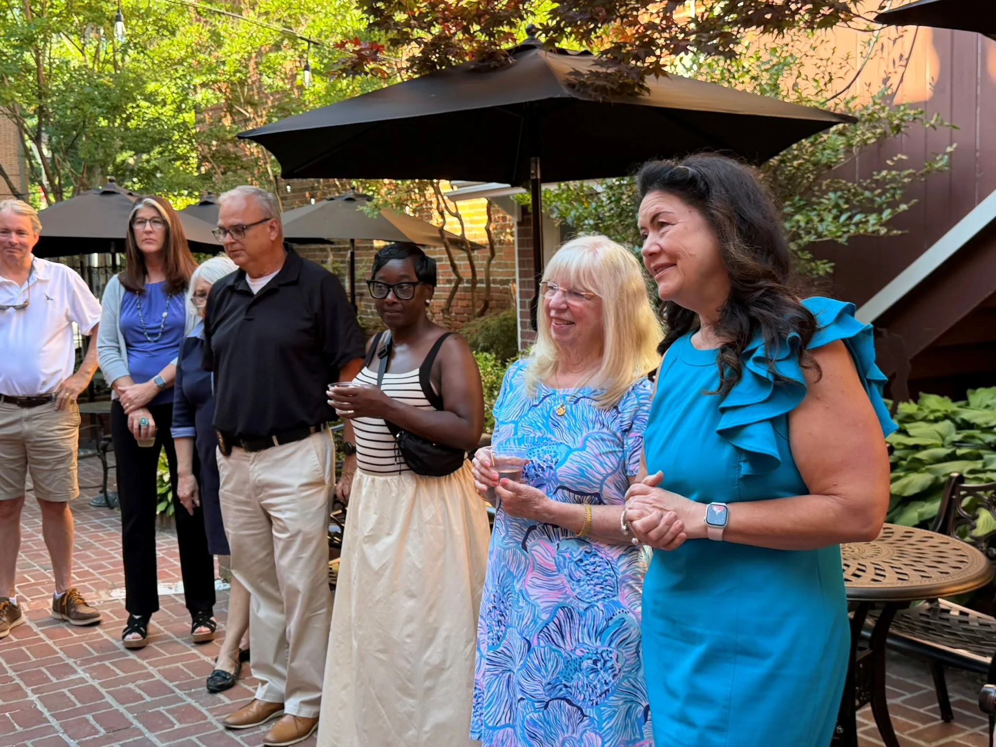 Guests holding drinks on a brick patio at an outdoor reception