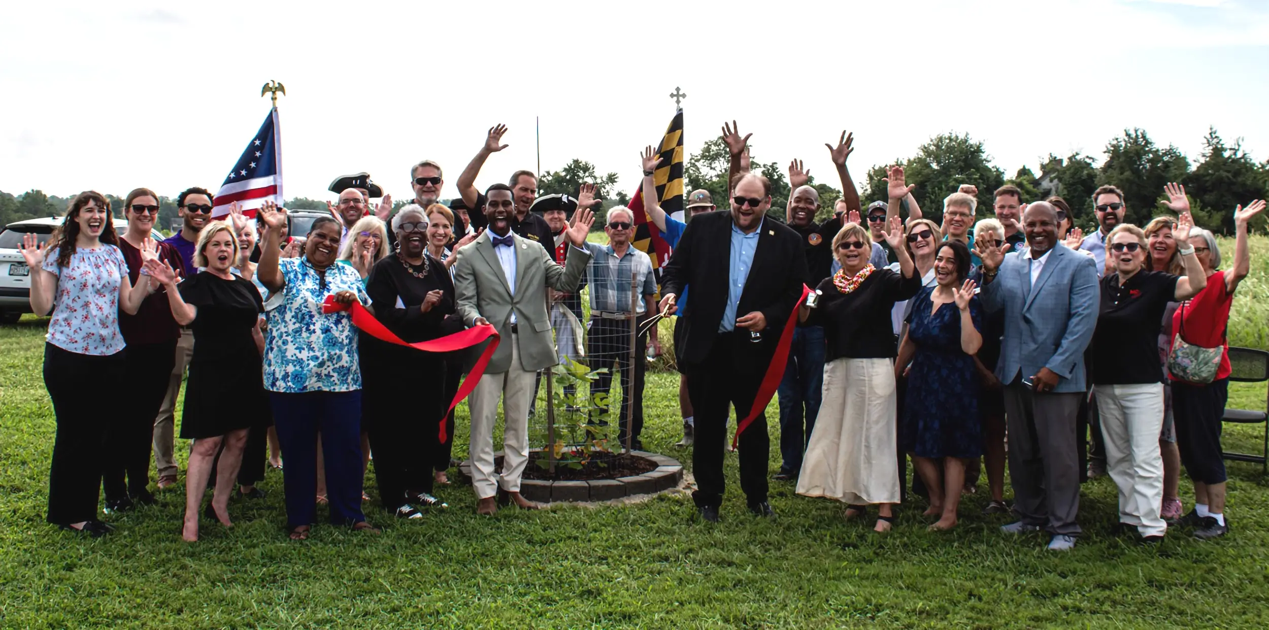 People cutting a ribbon at the Liberty Tree