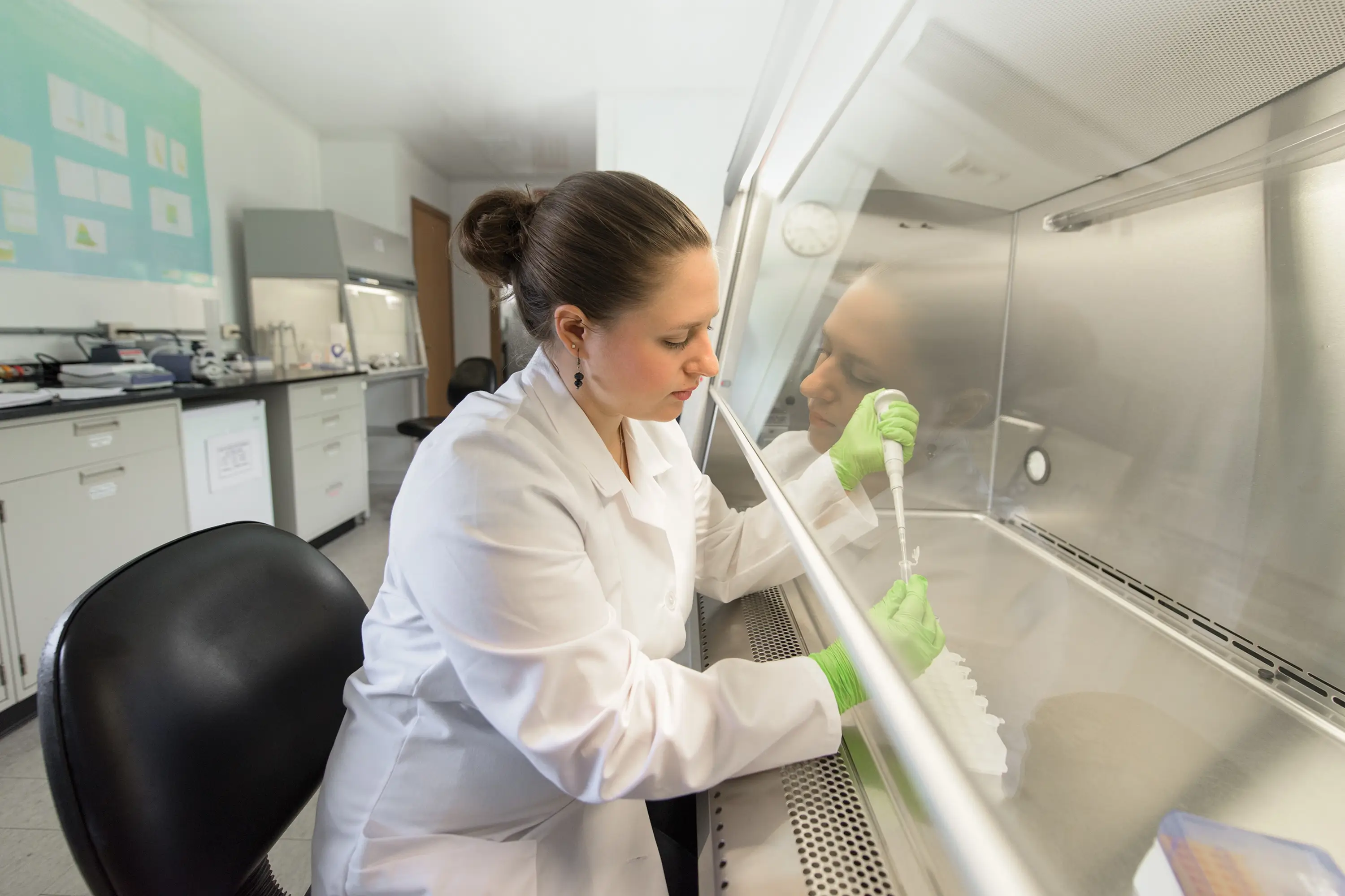 A woman with a pipette under a vented hood